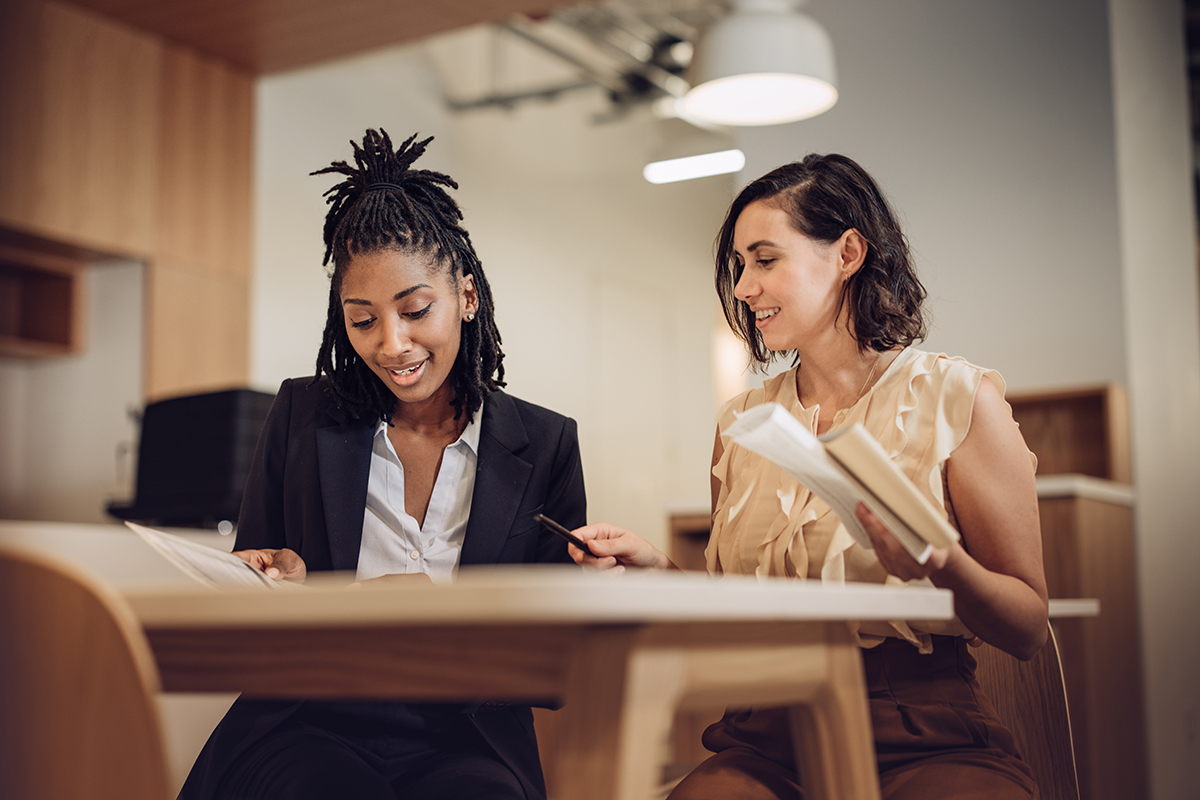 Two HR professionals collaborating over employee documents in a modern office, demonstrating supportive and people-focused human resources practice.