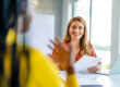 Smiling HR professional having a one-on-one meeting in a modern office, holding documents and engaging with a colleague.